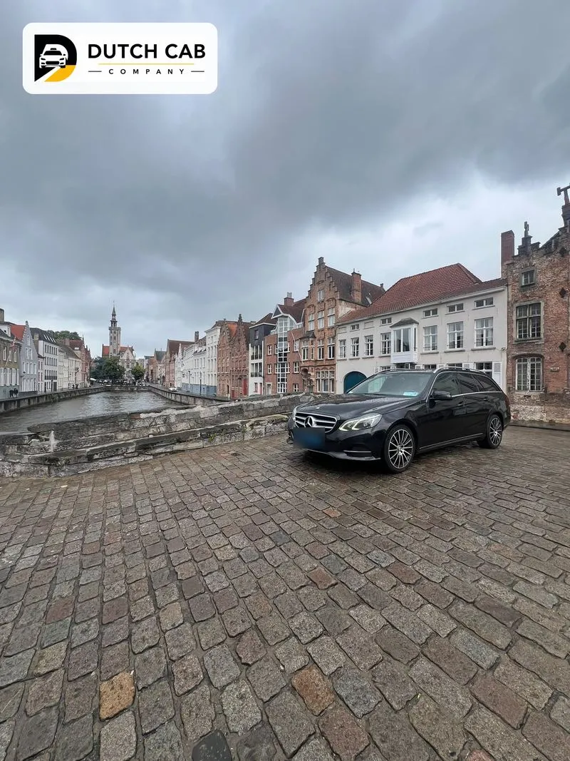 Zwarte Mercedes E-Klasse van Dutch Cab Company op een kasseienbrug aan een historische gracht